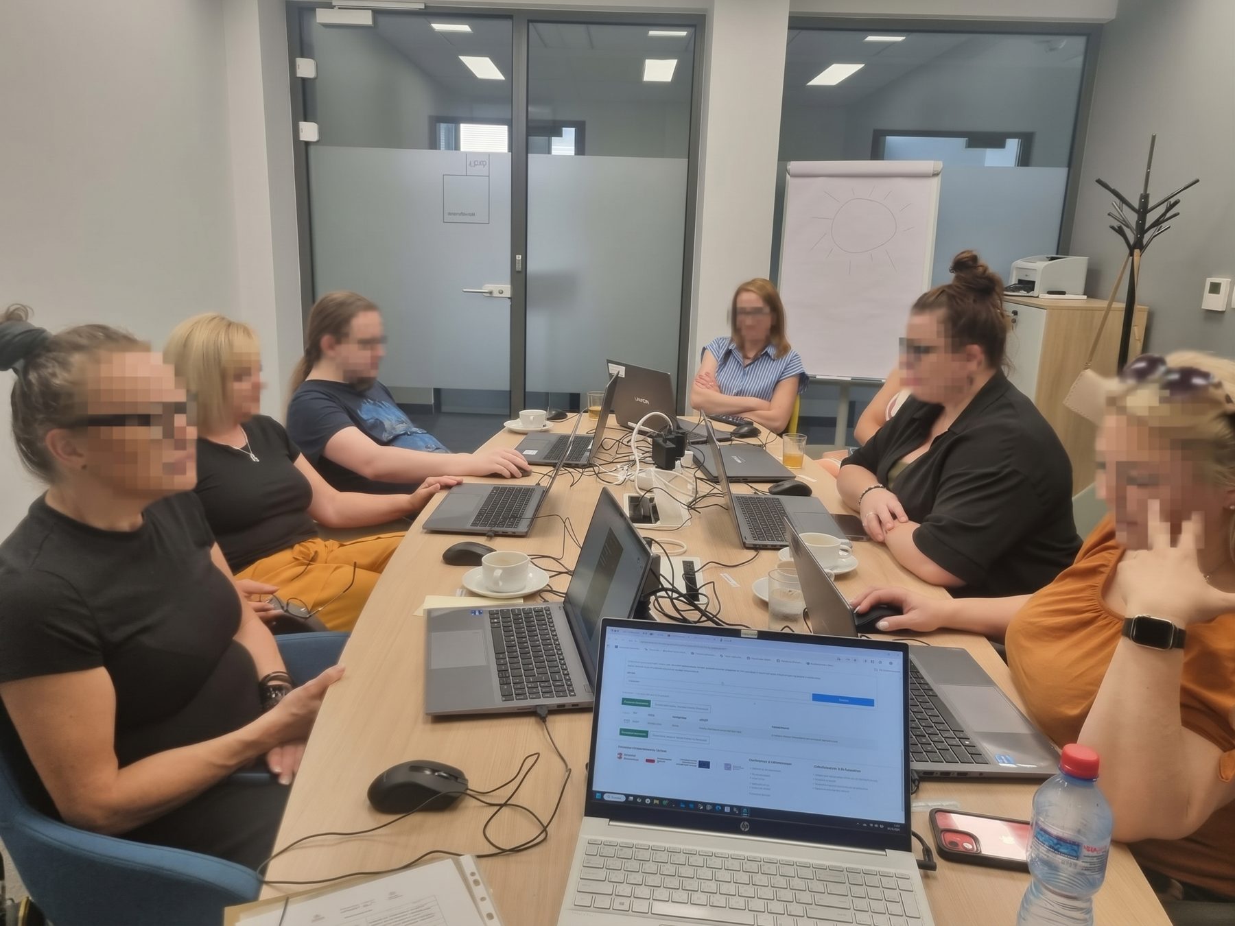 Uczestnicy warsztatów z AI Edu Imagine pracują na laptopach w sali konferencyjnej